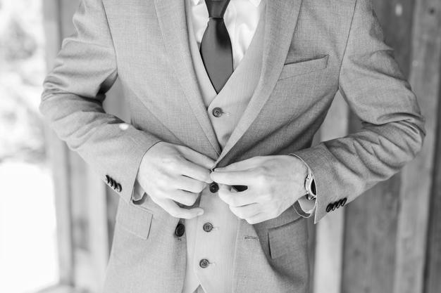 Groom buttoning coat on wedding day