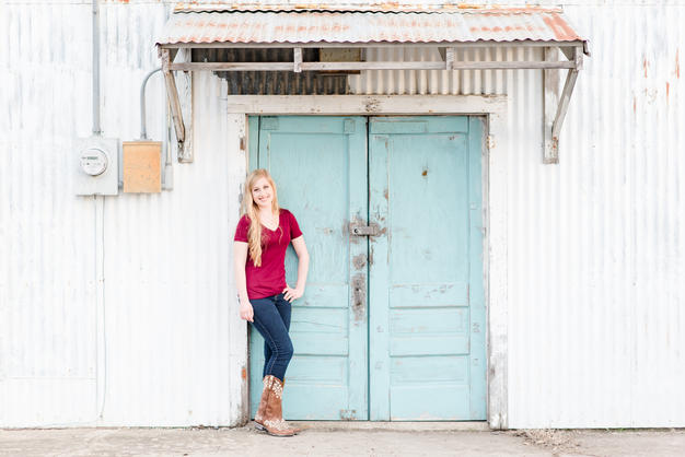 senior girl in front of turquoise doors
