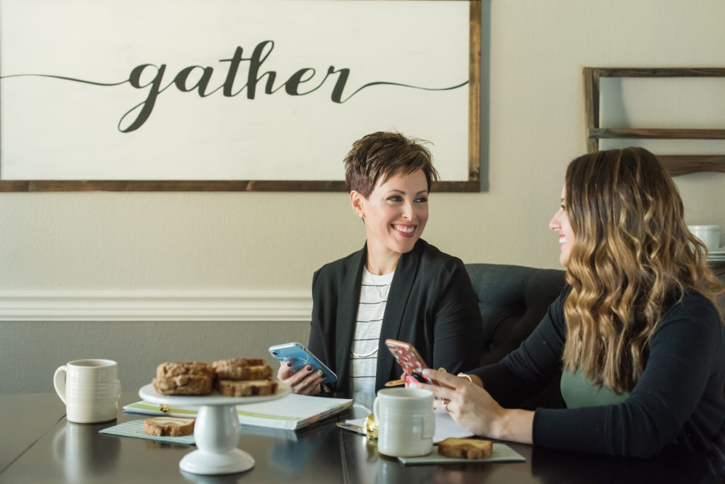 Two female business owners of a home based business sit at table and plan their day during their branding shoot