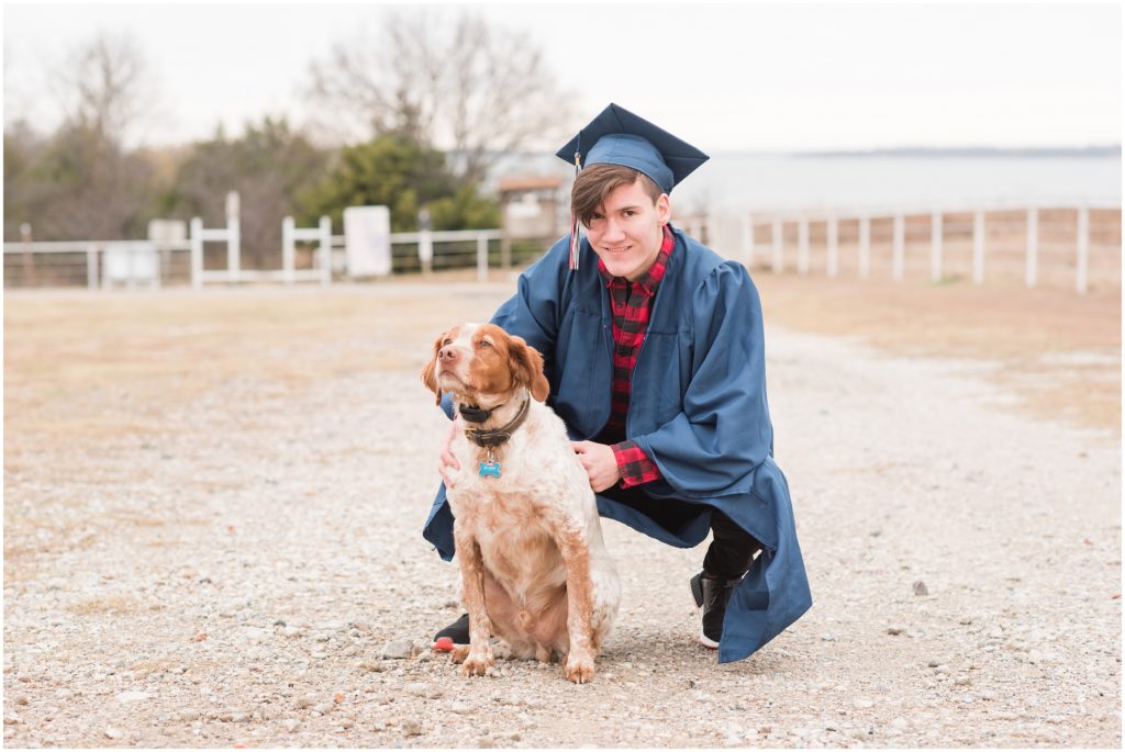 senior guy in cap and gown posing with dog