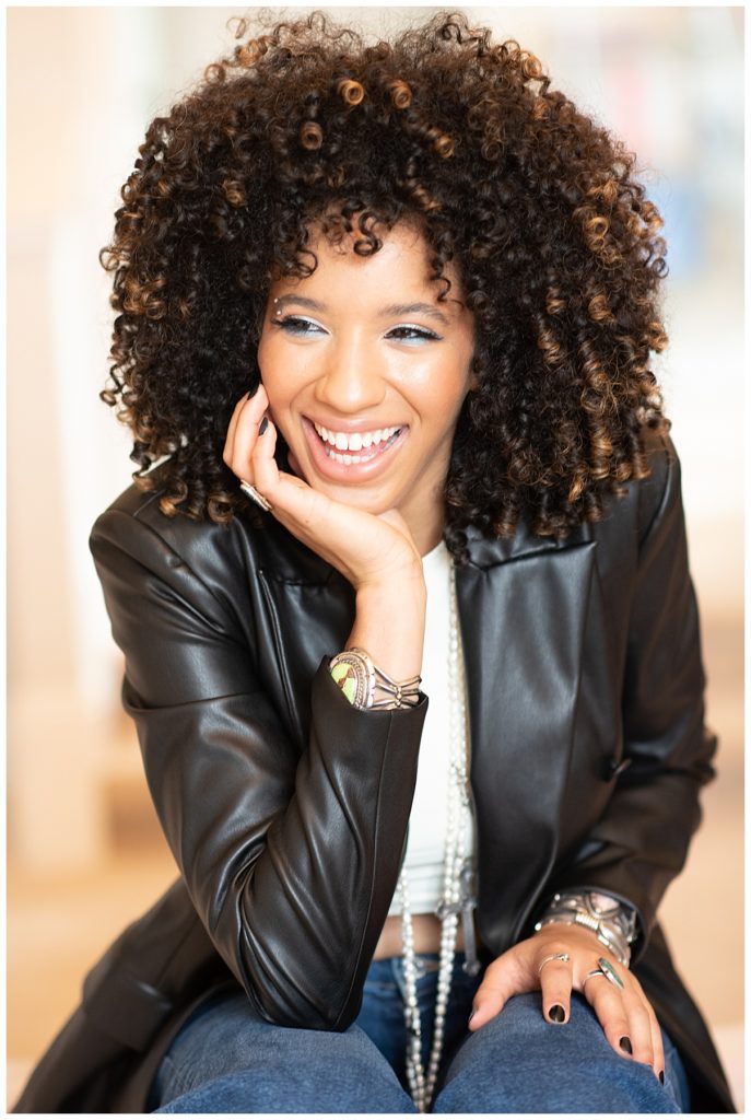 portrait of African American woman smiling off camera in black jacket and pearls